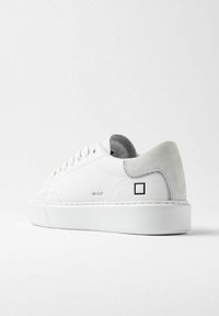 Sneaker bianco con tomaia in pelle liscia, tallone in suede grigio e suola in gomma. Presenta un branding minimale e un design pulito.