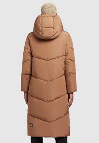 Abrigo acolchado largo y marrón con capucha. Presenta un acolchado en forma de chevron, un diseño ligeramente entallado y un parche de logo en el lateral. Material suave y ligero.