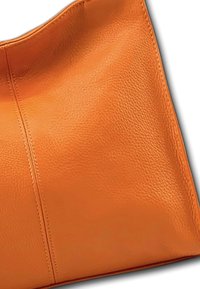 Oranje leren handtas met een zachte textuur, met een eenvoudig ontwerp en opvallende gestikte naaddetails aan de zijkant.