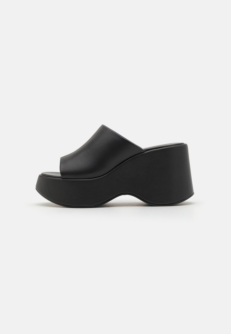 Sandales plateforme noires avec dessus en cuir lisse, design à bout ouvert, et semelle épaisse ondulée. Vue de côté mettant en valeur la hauteur et la forme.