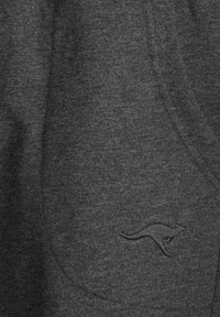 Dark gray sweatpants made of soft fabric, featuring a kangaroo logo embroidered on the side pocket and a relaxed fit design.