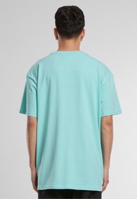 Tricou din bumbac de culoare albastră deschisă, cu un croi lejer, mâneci scurte și gât rotund, având o textură netedă și fără modele sau accente vizibile.