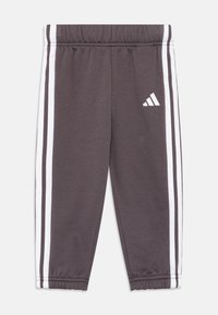 Pantalones deportivos grises de tejido suave, con franjas laterales blancas y un logo de Adidas en blanco, con una cinturilla elástica y puños ajustados.