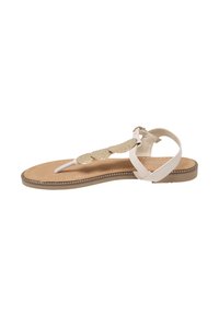 Beige flad sandal med tårem, ankelrem og dekorative guldløvformede pynt på den øverste rem.