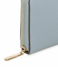 Jasnoniebieski portfel ze strukturalnej skóry z złotym zamkiem błyskawicznym i metką. Charakteryzuje się eleganckim designem z kontrastującym ciemnym wykończeniem wzdłuż krawędzi.