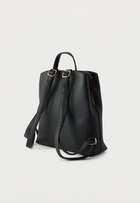 Μαύρο δερμάτινο σακίδιο με ρυθμιζόμενους ιμάντες, λαβή στο πάνω μέρος και χρυσό φερμουάρ σε απλό λευκό φόντο.