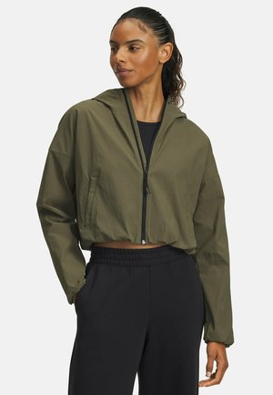 Cropped, olive green jacket with a hood, featuring a front zipper and long sleeves. Paired with black, elastic-waist sweatpants.