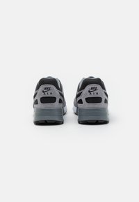 Zapatillas Nike Air grises con un upper texturizado, paneles de malla y suela de goma. Presentan acentos en negro y un logotipo prominente en el talón.