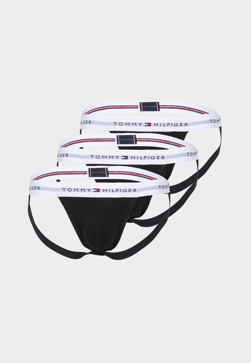 Drei Paar schwarze String-Unterwäsche mit weißen elastischen Taillenbändern und roten sowie blauen Akzenten, markiert mit "TOMMY HILFIGER."