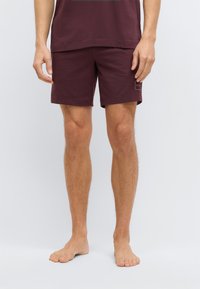 Burgundinpunaiset shortsit, joissa on rento istuvuus, tehty pehmeästä kankaasta, varustettu pienellä logopilkulla ja säädettävällä vyötäröllä.