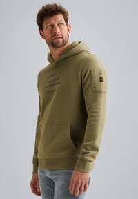 Olivově zelená mikina s kapucí a přední kapsou, utahovací kapuce a potiskem "AVIATOR ADVENTURE." Obsahuje boční kapsu na rukávu s knoflíkovými detaily.