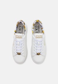 Hvite lær sneakers med en gullfarget Medusa-logo, med et fargerikt stofffôr og snøring. Kjennetegnet av merkevaredetaljer.