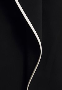 Gros plan sur un tissu noir avec une bordure blanche incurvée créant un contraste net et une ligne fluide et lisse.