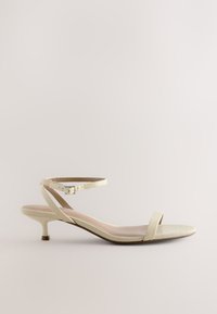 Sandale en cuir synthétique effet peau de serpent jaune clair, avec une fine bride à la cheville munie d'une boucle, un design minimaliste et un petit talon de 3 cm.