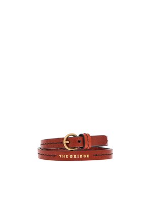 Bruine leren riem met gouden gesp en zwarte stiksels, geperst met de woorden "THE BRIDGE" in gouden letters.