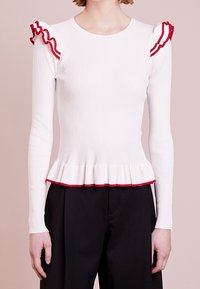 Weißes, geripptes Langarmoberteil mit roten Rüschendetails an den Schultern und dem Saum, im Peplum-Silhouette.