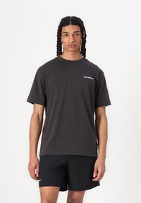 Dark gray cotton t-shirt with short sleeves and a crew neck; features a small white "new balance" logo on the left chest.