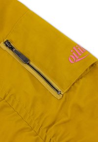 Geel jasje van stof met een gladde textuur, voorzien van een zijrits en een roze logo-accent in de buurt van de kraag.