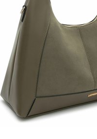 Borsa a tracolla verde oliva con una finitura morbida e testurizzata. Presenta un design elegante e angolare con accessori in metallo dorato. Chiusura con zip superiore.