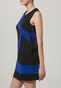 Černé a modré bezrukávové šaty s geometrickými barevnými bloky; mají kulatý výstřih a přiléhavý střih, vyrobené z hladké, texturované látky.