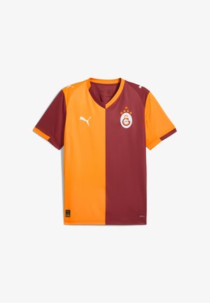 Camiseta de fútbol a mitades en rojo y naranja con cuello en v, logo blanco y tres estrellas sobre el emblema. Hecha de un material ligero y suave.