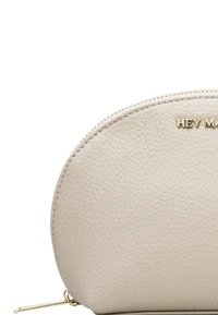 Pochette en cuir beige de forme arrondie, surface texturée, quincaillerie dorée et imprimé « HEY MA ». Fermeture zippée sur le dessus.