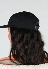 Casquette noire avec une visière plate et une sangle réglable à l'arrière. Le tissu semble lisse, sans motifs ni accents visibles.