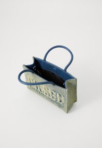 Petit sac à main en denim avec anses en cuir bleu, ouverture sur le dessus, poche intérieure et détail de logo embossé à l'avant. Surface texturée.
