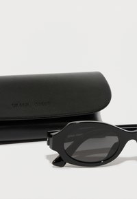 Gafas de sol negras de Giorgio Armani con una forma elegante y curvada y lentes oscuros, acompañadas de un estuche negro texturizado a juego.