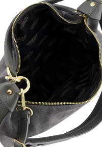 Gray suede handbag with gold zipper and black inner lining. Features a leather strap and interior pockets. Brand logo visible on lining.