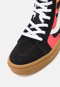 Wysokie sneakersy z czarną zamszową cholewką, różowymi akcentami, białymi sznurowadłami i gumową podeszwą. Posiadają haftowany wzór i fakturowe wykończenie.