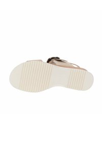 Sandal plano con un upper de color marrón claro y una suela de goma blanca que presenta surcos horizontales para mayor tracción y un detalle decorativo en forma de hebilla.