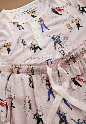 Katoenen pyjama set met een lichtroze achtergrond en een skaterprint. Het bovenstuk heeft een knoopsluiting en de broek heeft een elastische tailleband.
