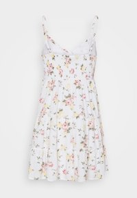 Bloemen zonnejurk met een witte stof met roze en gele bloemen. Het heeft verstelbare spaghetti bandjes en een geplooide rok.