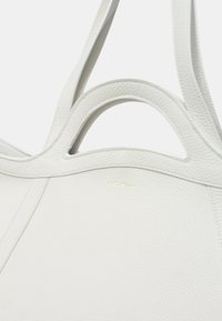 Borsa a spalla in pelle bianca con superficie texture, manici curvi doppi e design minimalista con logo goffrato discreto.