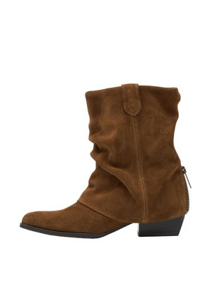 Botte marron en daim mi-mollet avec talon bloc bas, bout pointu et détail zippé à l'arrière.