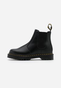 Stivali Chelsea in pelle nera con pannelli laterali elasticizzati, dettagli in cucitura gialla e suole in gomma testurizzata. Presentano un manico sul tallone.
