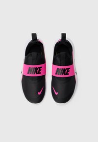 Une paire de baskets noires Nike à enfiler avec de larges bandes élastiques roses et des swooshes roses sur des semelles blanches, vue de dessus.