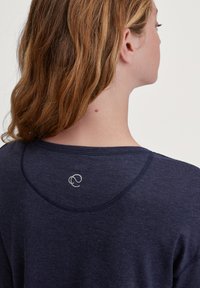 Marineblauwe langemouwen top van zachte stof, met een ronde halslijn en een subtiel logo op de achterkant. Soepele textuur en een comfortabele pasvorm.