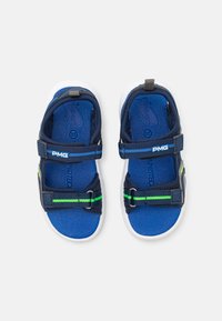 Sandales bleu marine avec des sangles en tissu, fermetures réglables et semelle intérieure bleue rembourrée. Semelle en caoutchouc blanche, avec des rayures vertes accentuées.