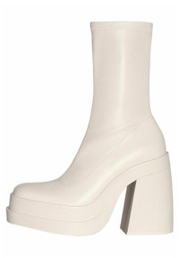 Beige nilkkurit, joissa on sileä, joustava muotoilu, neliömäinen kärki ja korkea paksu korko. Valmistettu sileästä materiaalista, jossa on vain vähäisiä ompelusaumoja.