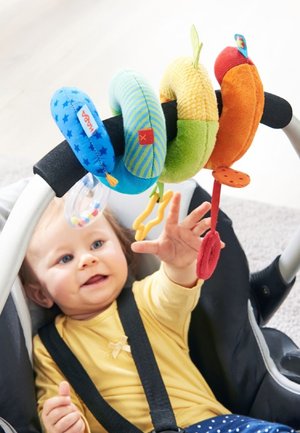 Bunte Stoffspielzeugspiralen in Blau, Grün, Gelb und Orange, die an einem Kinderwagengriff befestigt sind. Enthält verschiedene Texturen und verspielte Muster.