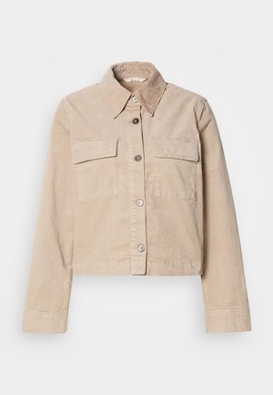 Beige verkürzte Jacke aus Baumwolle. Verfügt über einen spitzen Kragen, zwei Vorderaschen und einen Knopfverschluss. Texturiert mit einem subtilen Glanz.