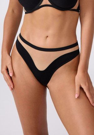 Czarne bikini dolne z przezroczystymi panelami, w kształcie litery V z przodu i cienkimi, czarnymi ramiączkami. Miękka tekstura w kontrastowym odcieniu do koloru skóry.