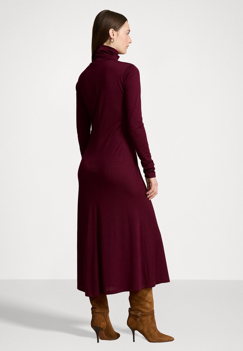 Bordeauxfarbendes Rollkragenkleid mit langen Ärmeln, tailliertem Oberteil und fließendem Rock, kombiniert mit hellbraunen High-Heels.