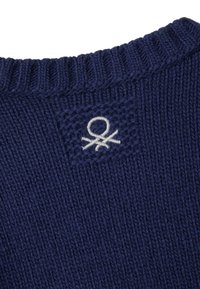 Náměrově modrý pletený svetr s žebrovaným výstřihem a texturovanou tkaninou, s bílým vyšívaným logem na zadní straně.