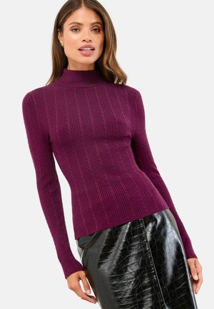 Pulover tricotat cu dungi violet, cu guler înalt și mâneci lungi, asortat cu o fustă creion neagră lucioasă, cu textură de crocodil.