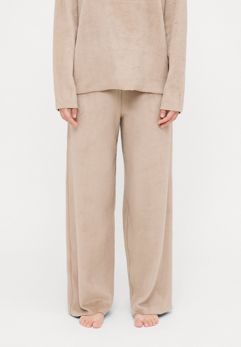 Beige fleece loungewear set featuring a long-sleeve top and wide-leg pants, both with a soft texture and relaxed fit.