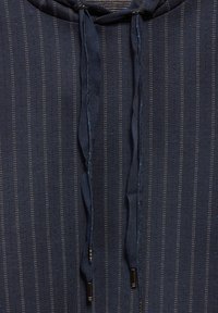 Marineblaues Hoodiekleid mit vertikalen Streifen, ausgestattet mit einer strukturierten Stoffoberfläche und Kordeln mit Metallspitzen. Das Design enthält dezente blaue Akzente.