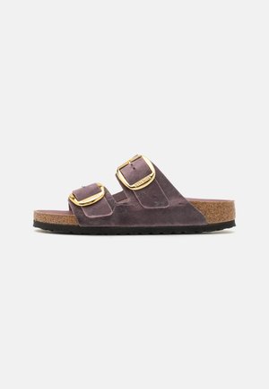 Sandalo slide in suede viola con due cinturini regolabili in oro, una soletta in sughero e una suola in gomma nera texturizzata.